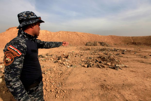 A member of Iraqi security forces gestures towards a mass grave for corpses in the town of Hammam al-Alil which was seized from Islamic State last week.